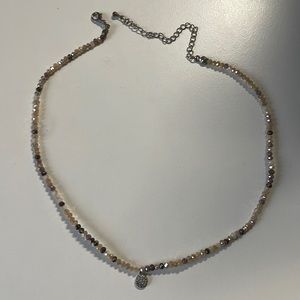 Varied hues of brown and tan jewels with a silver pendant necklace.